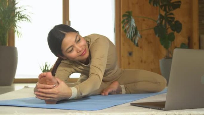特写: 亚洲女性观看在线瑜伽训练并练习坐姿