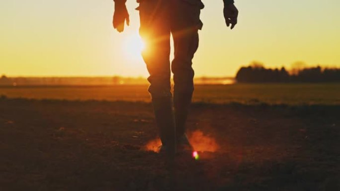 日落时分，穿着胶靴的SLO MO Farmer穿过田野