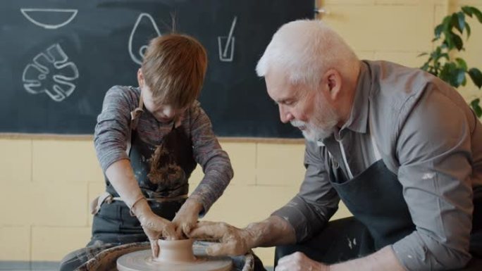 祖父和孙子用陶轮上的粘土制造陶瓷锅
