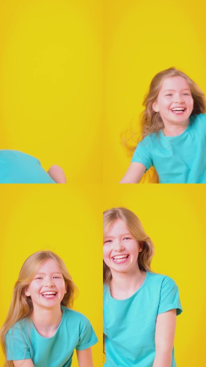 长发女孩旋转并在黄色背景下大笑的垂直视频-慢动作拍摄