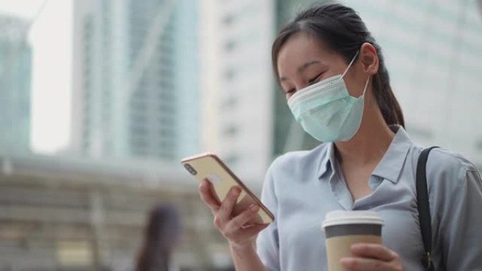 亚洲女商人在城市使用带口罩的手机