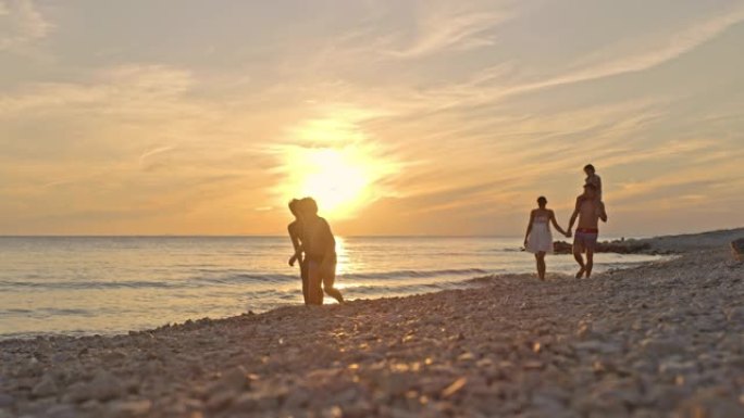 SLO MO一家，三个孩子在日落时在海滩上散步