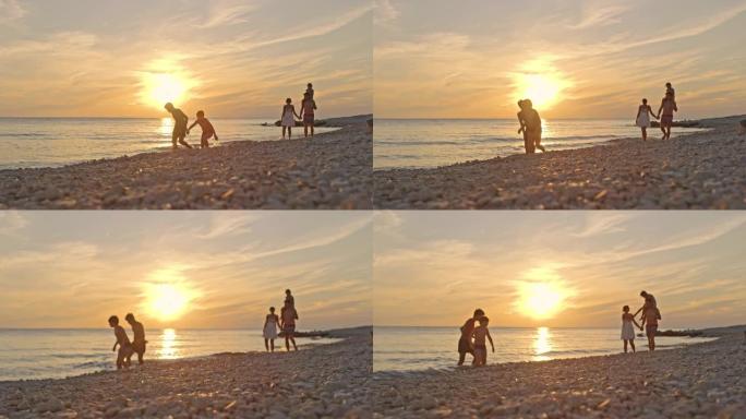 SLO MO一家，三个孩子在日落时在海滩上散步