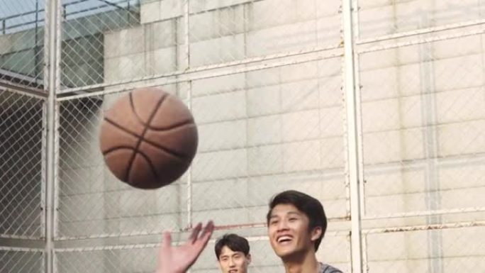 年轻的亚洲男子在室外球场上打篮球