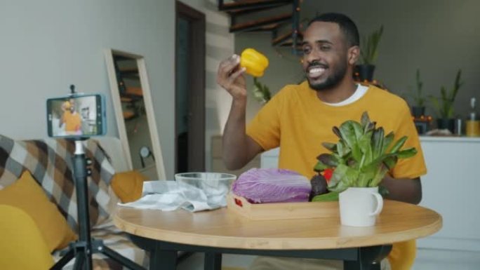 创意男子录制烹饪视频视频，在家中使用智能手机摄像头展示高五手势蔬菜