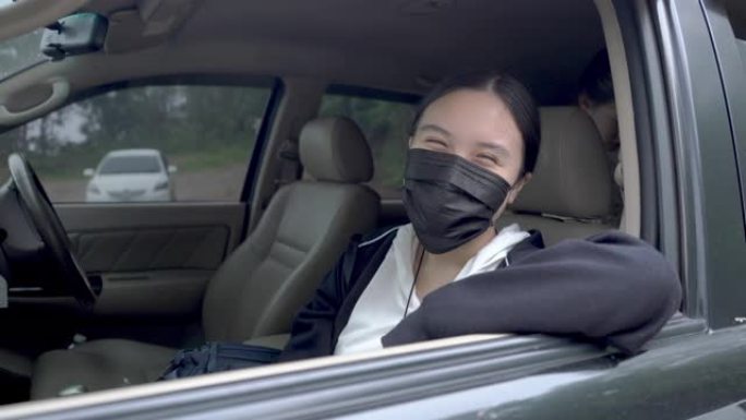 在新型冠状病毒肺炎冠状病毒大流行期间，十几岁的亚洲女孩在汽车上戴着防护口罩微笑，家人在背景下微笑