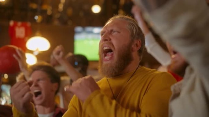 兴奋的足球俱乐部成员在酒吧为他们的球队欢呼。支持球迷站在酒吧里，欢呼，举手并大喊大叫。朋友在进球后庆