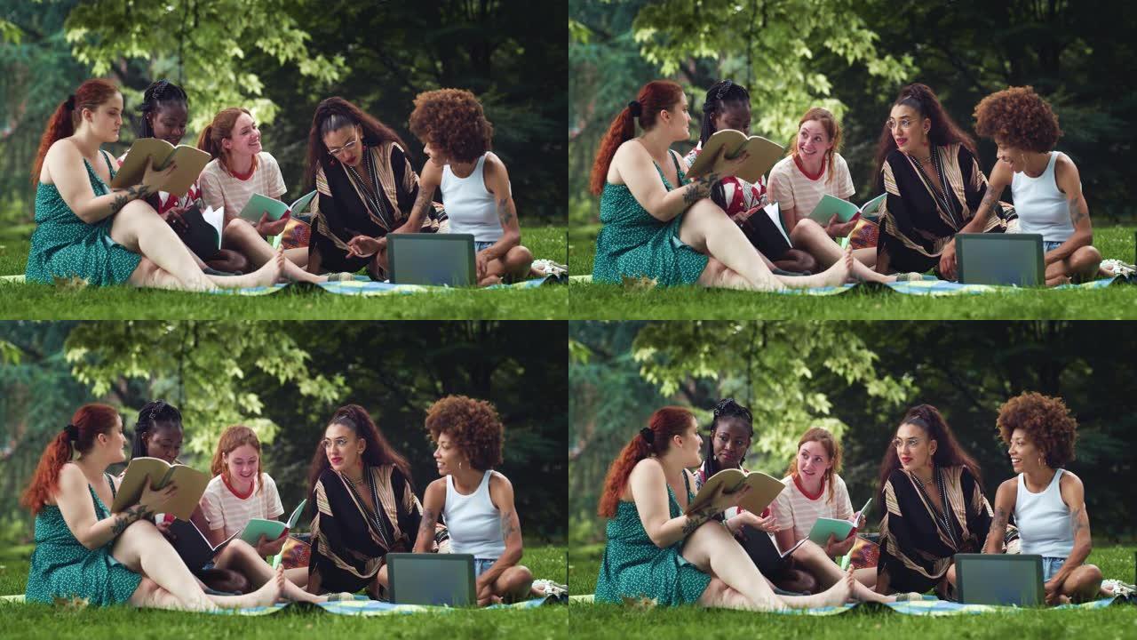 各种各样的女性朋友讨论和使用笔记本电脑。一群多种族的女学生在户外大学项目中工作，并享受夏季的好天气