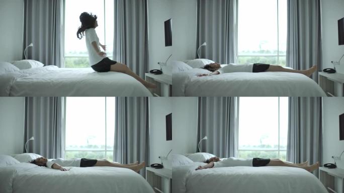 亚洲女子在真实的慢动作中摔倒在床上