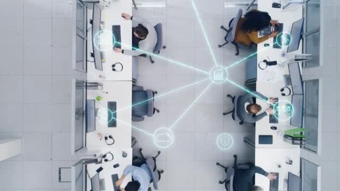 一个繁忙的公司办公室的自上而下的镜头，其中有两排在台式计算机上工作的商人和女商人。同事之间互联技术社