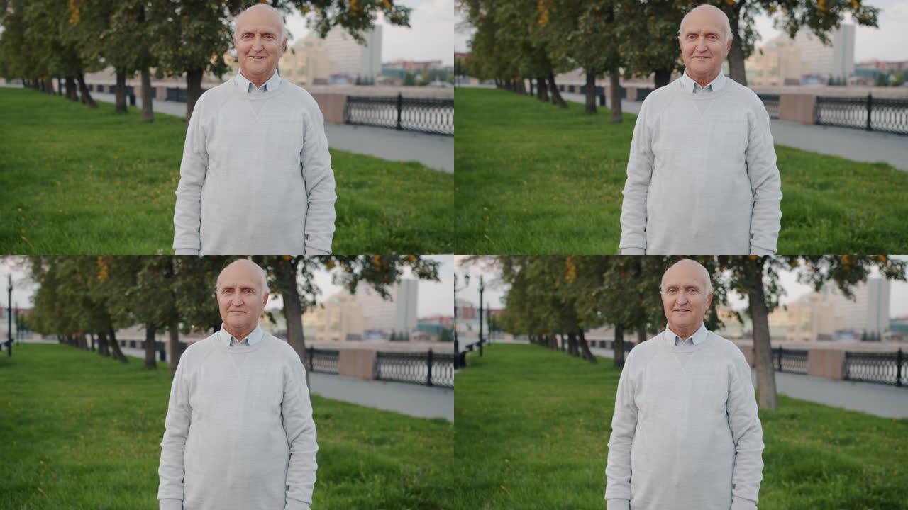 快乐的老人微笑着看着站在城市户外的相机的慢动作肖像