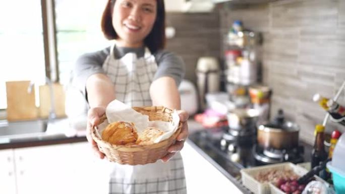 女厨师在前面拿着羊角面包并展示