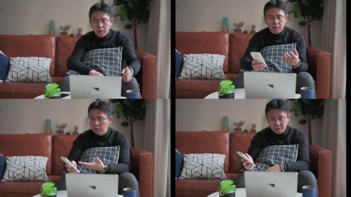 中年中国成年人在家工作，带笔记本电脑坐在沙发客厅，带笔记本电脑和智能手机