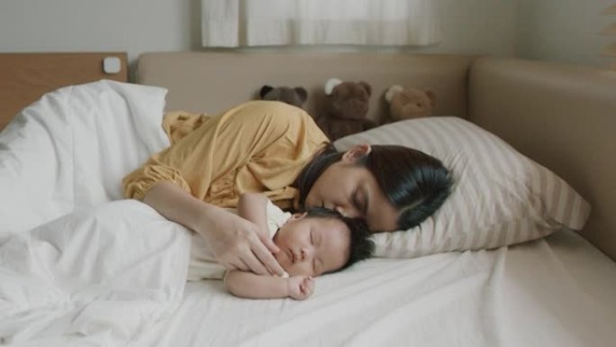 年轻的母亲拥抱婴儿睡觉。