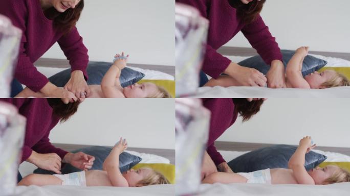 高加索母亲在家里的床上给婴儿换尿布