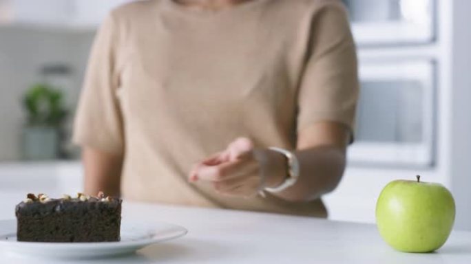 4k视频片段，一个无法识别的女人决定在家中吃苹果还是巧克力布朗尼