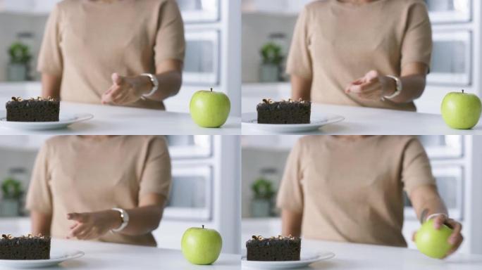 4k视频片段，一个无法识别的女人决定在家中吃苹果还是巧克力布朗尼