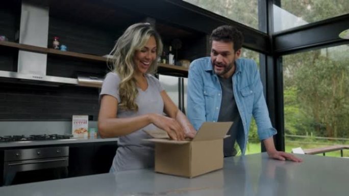 幸福的夫妻从网上购物中打开一个盒子，看着产品时非常兴奋