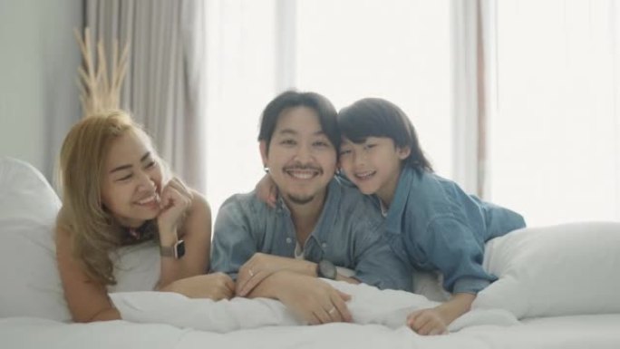 一个幸福家庭的肖像在家里。有趣快乐的一家人在床上挠痒痒