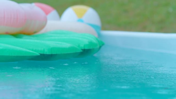 特写: 雨滴落入空的绿松石水和五颜六色的漂浮物中。