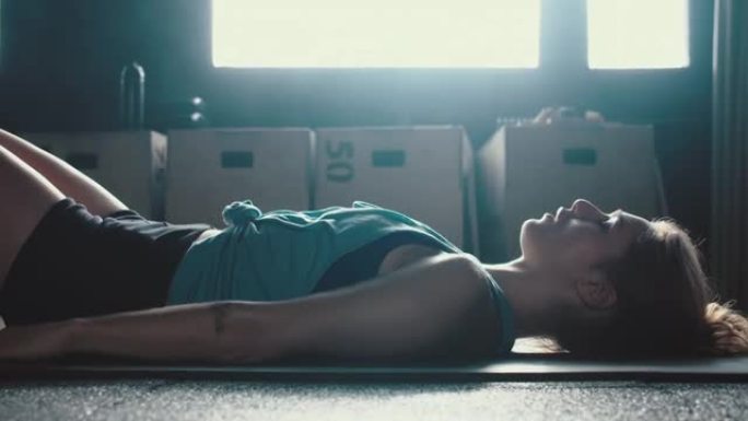 健身追踪器手表应用程序运动的年轻女子躺在带手镯的瑜伽垫上做腹肌练习，观察进步。