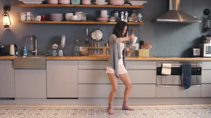 4k视频片段，一名年轻女子在家里的厨房里跳舞时喝咖啡