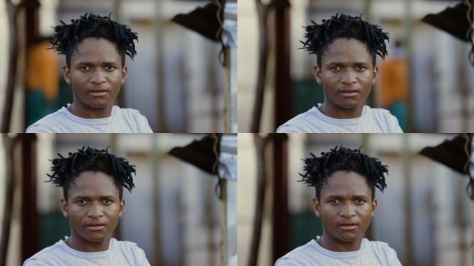 贫穷。不平等。一个黑人非洲男子在贫民窟周围看着相机的特写肖像。