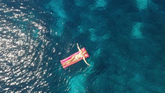 空中女子在漂浮在亚得里亚海绿松石水上的水池筏上放松