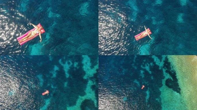 空中女子在漂浮在亚得里亚海绿松石水上的水池筏上放松