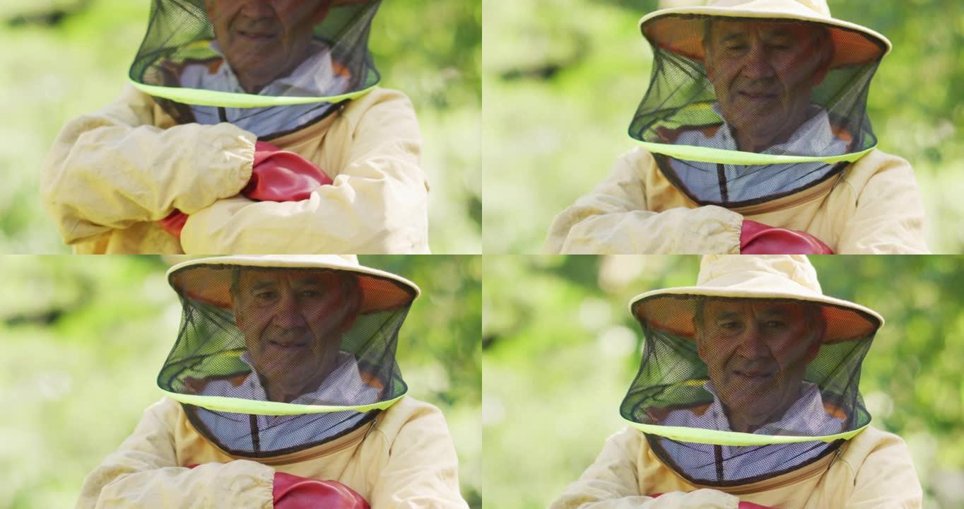微笑的白人男性养蜂人的肖像，穿着双臂交叉的防护服
