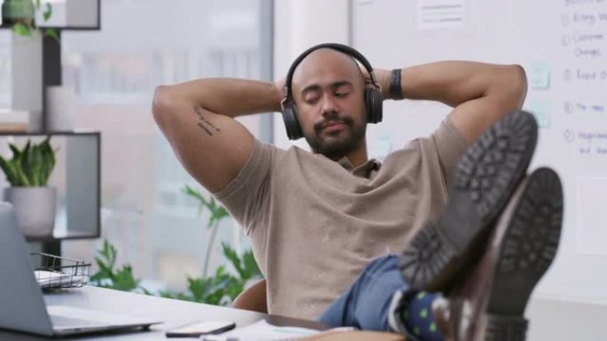 一个英俊的年轻商人独自坐在办公室里通过耳机听音乐的4k视频片段