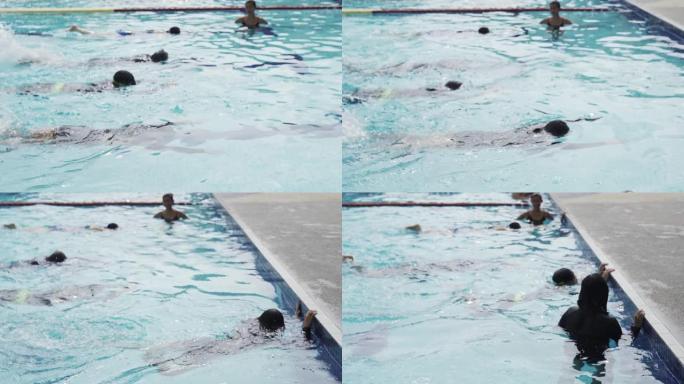 亚洲中国游泳运动员在游泳教练的指导下在游泳池边练习游泳