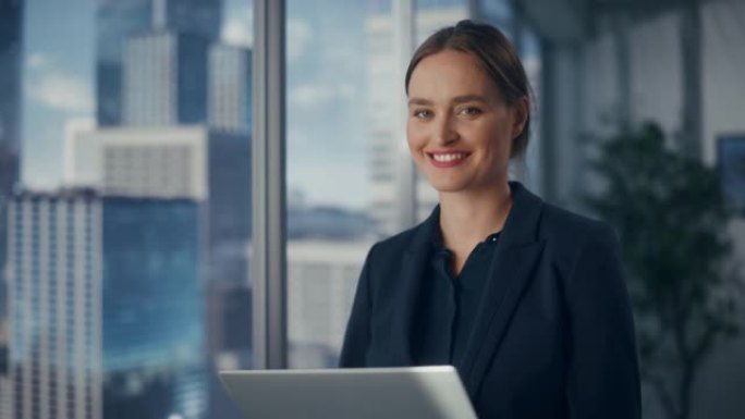 成功的女商人穿着时髦的衣服在笔记本电脑上工作，站在大城市的窗户旁边。自信的女CEO分析金融项目。工作