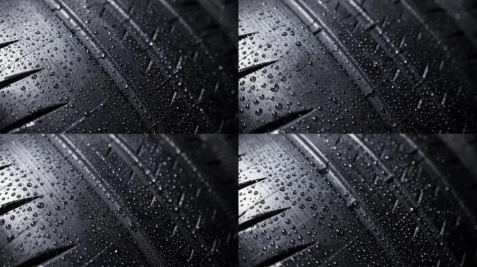 黑色背景下的新车夏季轮胎胎面花纹上的水滴