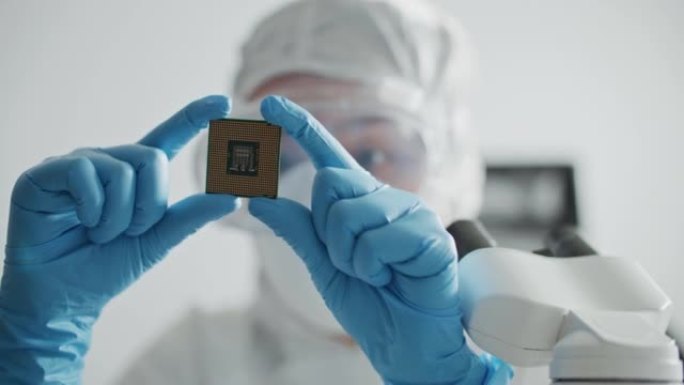 无菌工作服工程师戴着手套拿着计算机微芯片并对其进行检查