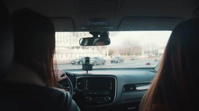 城市驾驶压力。从车内看，两名妇女在繁忙的大城市街道上乘坐私人车辆时交谈。