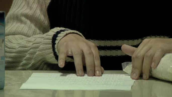 一名年轻学生的手在阿根廷的一所公立学校为盲人和视障儿童阅读盲文字母。特写。