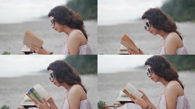 迷人的年轻女孩坐在沙滩上看书