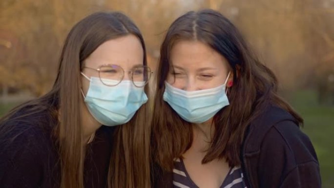两名十几岁的女孩在户外见面时戴着防护口罩