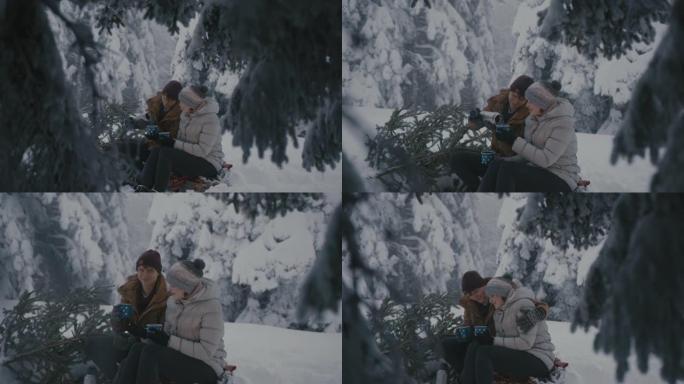 夫妇带着圣诞树在白雪覆盖的森林里享受热饮