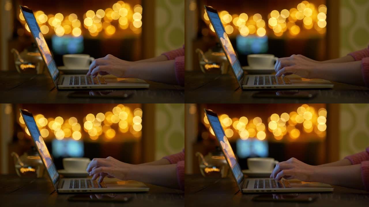 女性手在笔记本电脑上打字。女人在电脑工作或写书。家里或咖啡馆舒适的氛围。背景下温暖的橙色bokeh圆