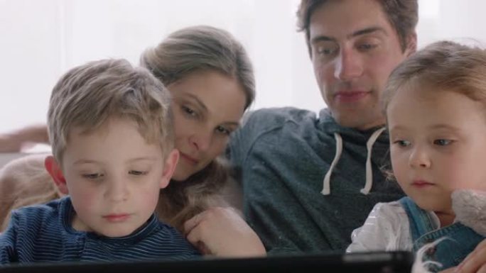 家庭幸福家庭在家使用平板电脑父母带着孩子在触摸屏设备上观看娱乐游戏学习一起玩乐4k镜头