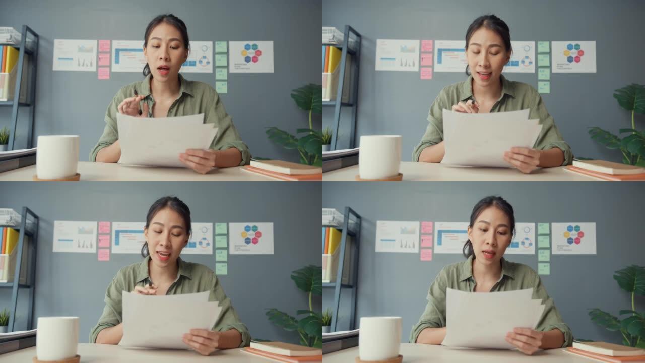 亚洲女商人在客厅在家工作时，使用笔记本电脑与同事讨论视频通话计划。远程工作场所，社交距离，检疫冠状病