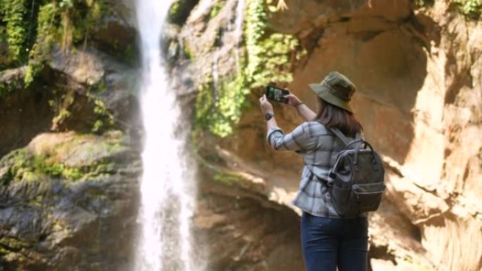 女人徒步旅行到绿色森林的瀑布