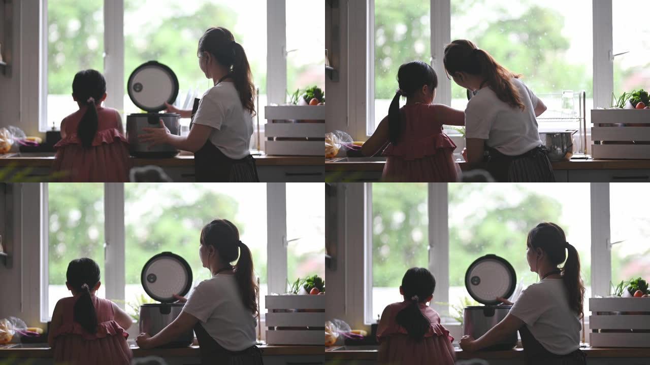 亚洲华裔母亲在厨房做饭，女儿用电饭煲煮饭