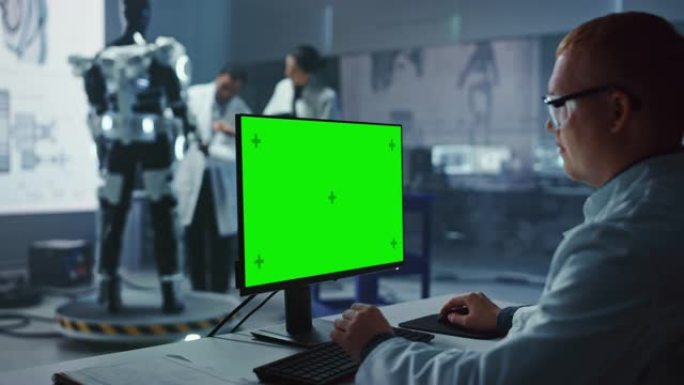 在开发实验室: 首席分析师使用绿屏计算机，科学家和工程师在机器人外骨骼原型上工作。设计Exosuit