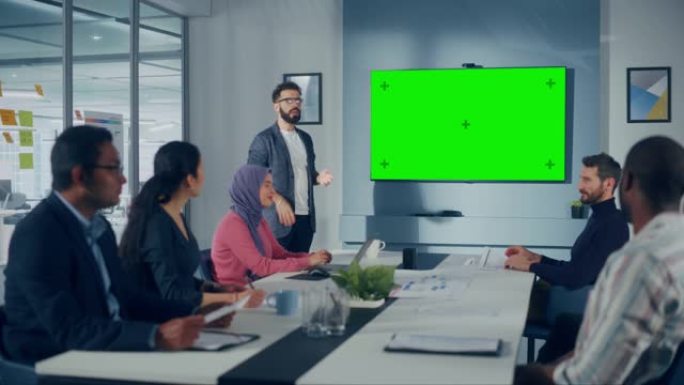 办公室会议室会议演示: 西班牙裔商人谈话，使用绿屏色键墙电视。成功向多民族投资者群体展示产品。电子商