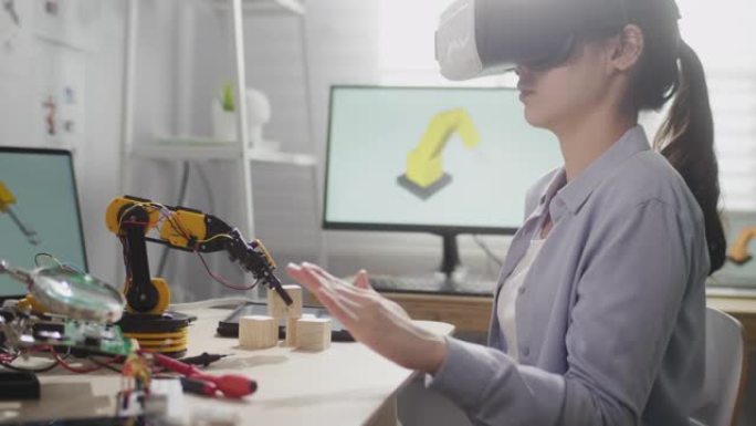 虚拟现实眼镜的女工程师移动手，用于控制办公室的机械臂