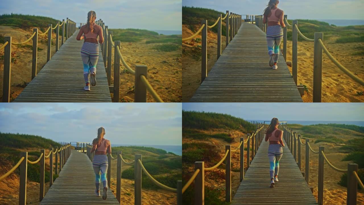 在海滩上的木制人行道上奔跑的女黑发运动员的手持跟踪照片