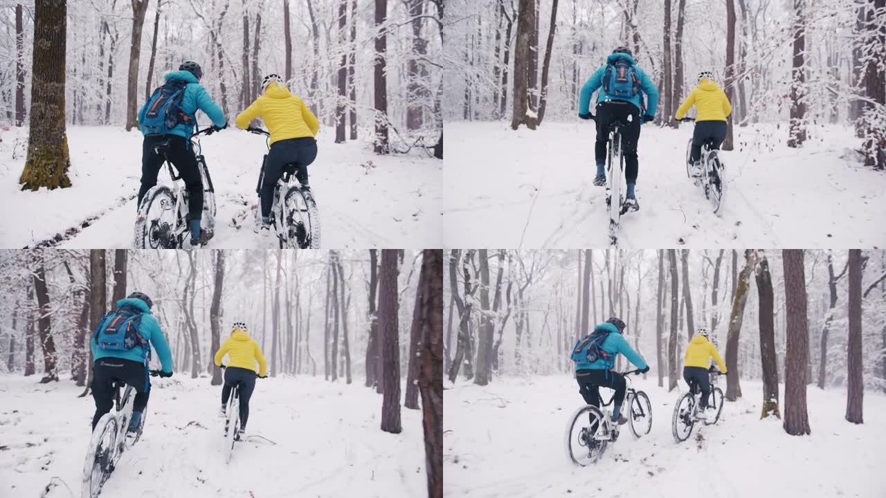 Slo mo两名骑自行车的人在白雪覆盖的森林中给自己高五
